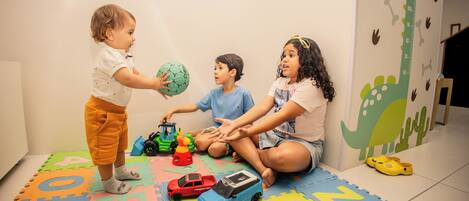 Children playing with toys on a colorful foam mat.