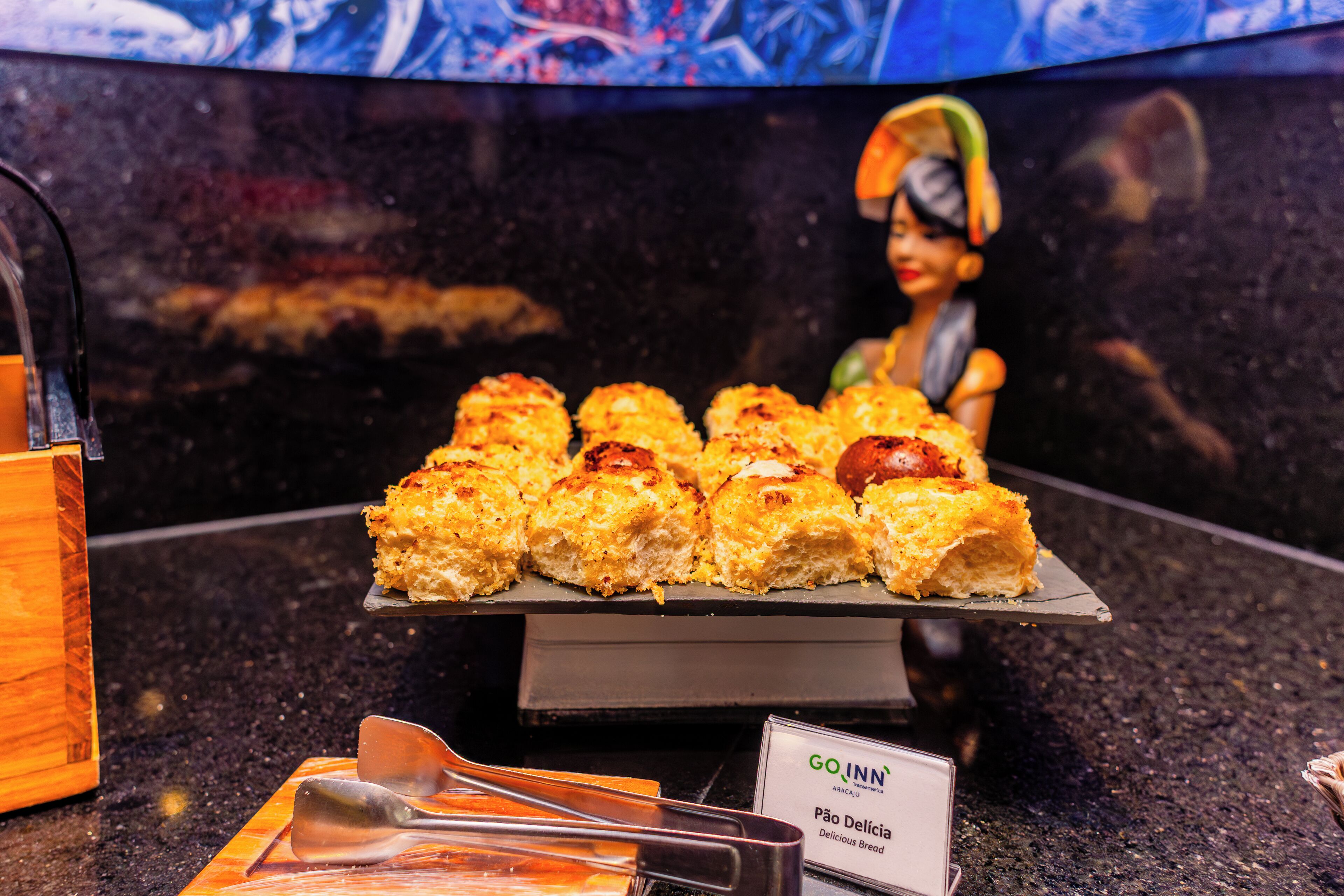 Una exhibición de pan con un letrero que dice 'GO INN Pão Delícia'.