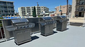 Three commercial-grade barbecue grills on an outdoor patio. - Royal Canadian Motel (Wildwood)