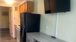 A compact kitchen with a refrigerator, microwave, and a TV mounted on the wall. - Royal Canadian Motel (Wildwood)
