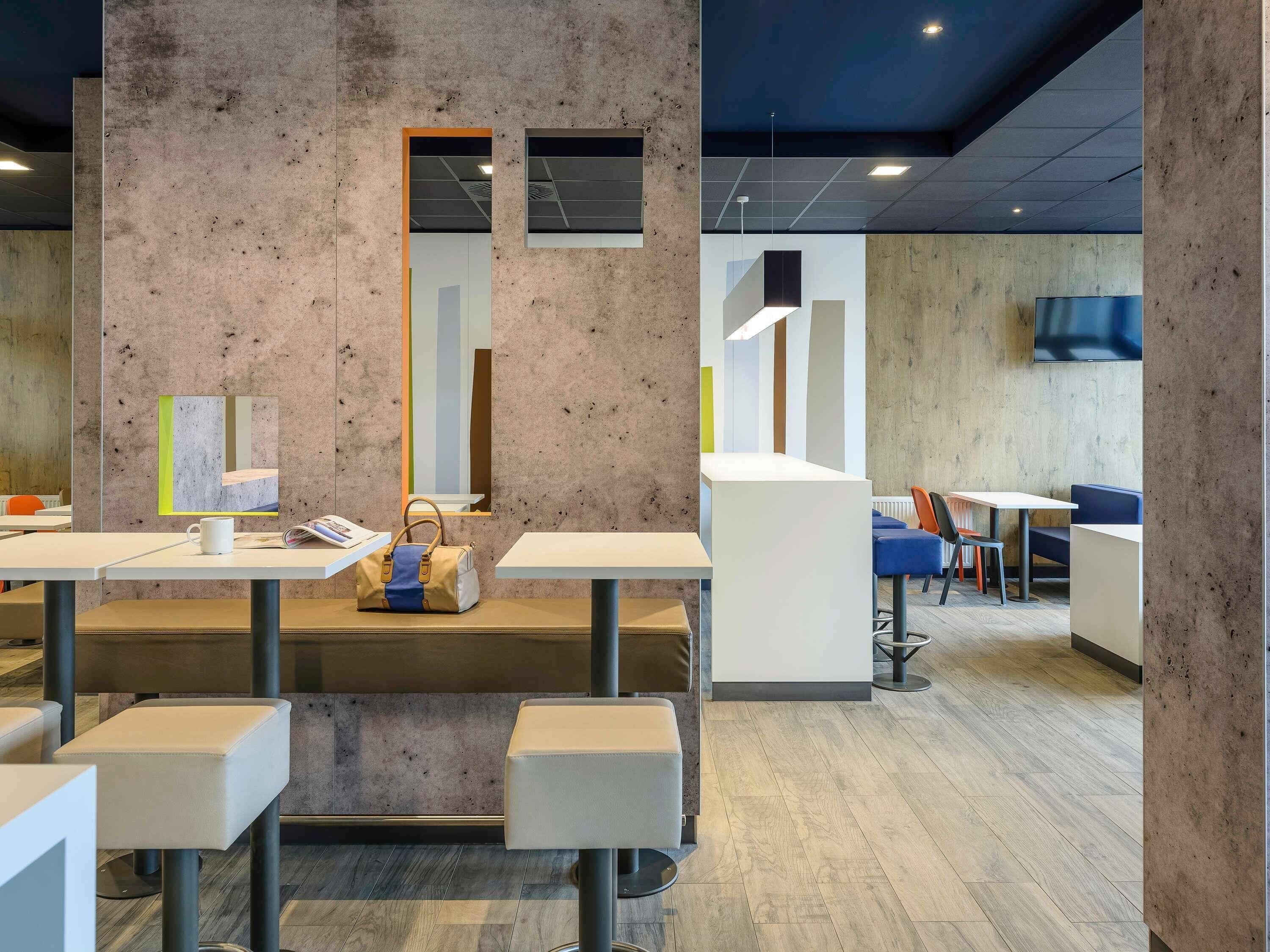 A modern interior with concrete walls, a central white table, and seating areas.