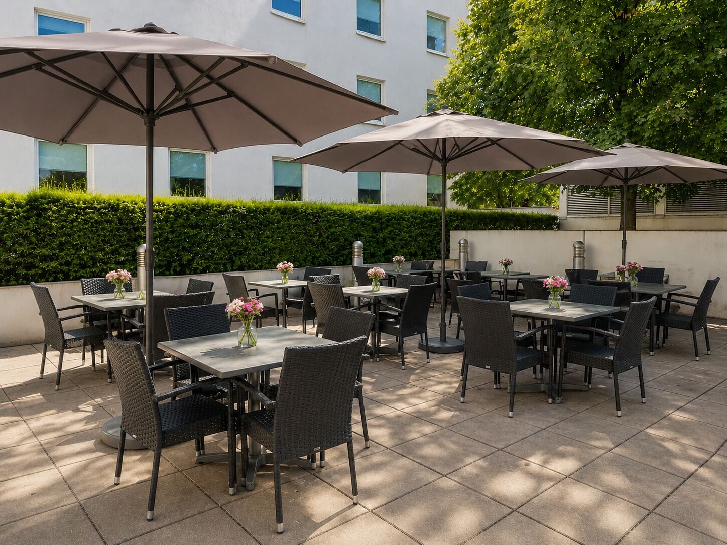 Une terrasse extérieure avec des tables et des chaises, des parasols et des arrangements floraux.