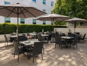 Un patio al aire libre con mesas, sillas, sombrillas y arreglos florales.