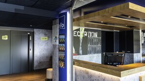A reception area with a marble counter, a blue information stand, and an elevator. - ibis budget Lyon Gerland (Lyon)
