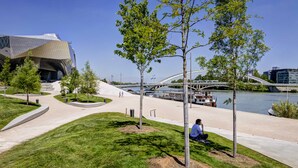 A modern urban park with a river, a bridge, and a distinctive building. - ibis budget Lyon Gerland (Lyon)
