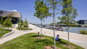 A modern urban park with a river, a bridge, and a distinctive building. - ibis budget Lyon Gerland (Lyon)