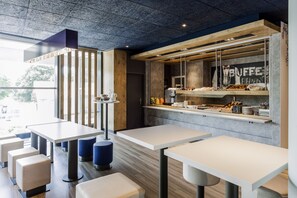 Enjoy a meal in our dining area, featuring a central counter with a glass display case and comfortable seating.