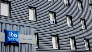 A modern building facade with horizontal lines and rectangular windows. A sign indicates the property is an ibis budget hotel. - ibis budget Lyon Gerland (Lyon)