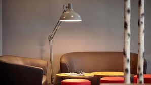 A modern lounge area with leather seating, a standing lamp, and round tables. - hotelF1 Paris Porte de Châtillon (Paris)