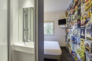 A bathroom with a shower, a sink, a bench, and a wall decorated with travel posters. - hotelF1 Paris Porte de Châtillon (Paris)
