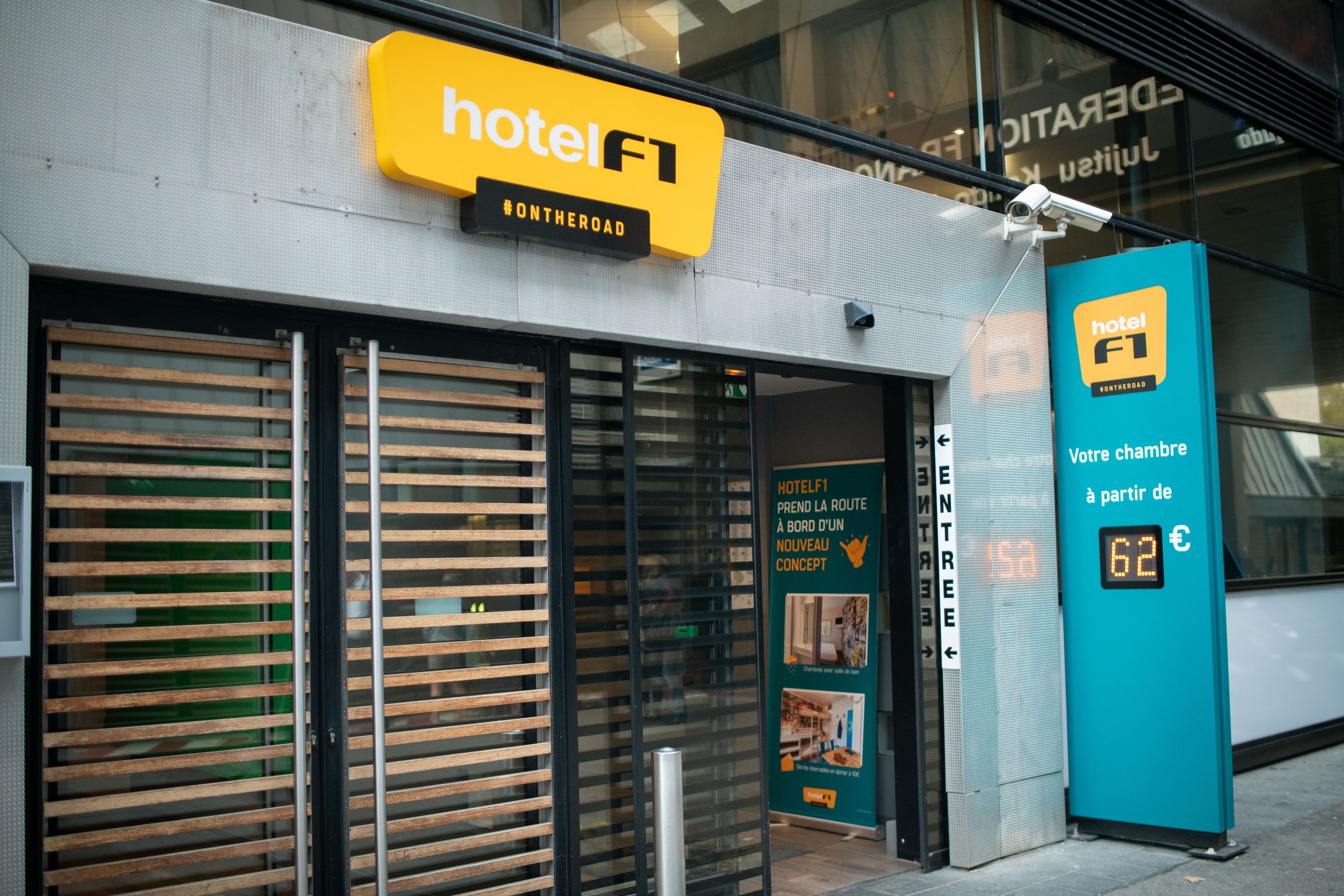 A hotel entrance with a sign reading "hotel F1" and a digital display showing room rates.