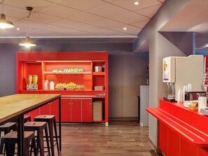 A modern restaurant interior with a red counter, wooden stools, and a variety of food items displayed on shelves. - hotelF1 Paris Porte de Châtillon (Paris)
