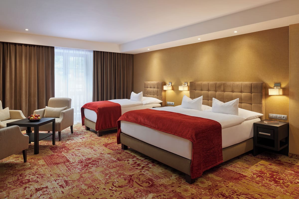 A hotel room with two beds, a sofa, a small table, and a carpeted floor.