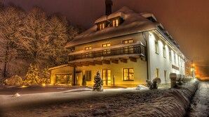 Un grand bâtiment à deux étages, dont le toit est recouvert de neige et qui possède de nombreuses fenêtres.