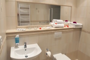 A bathroom with a sink, mirror, towel rack, and a toilet.