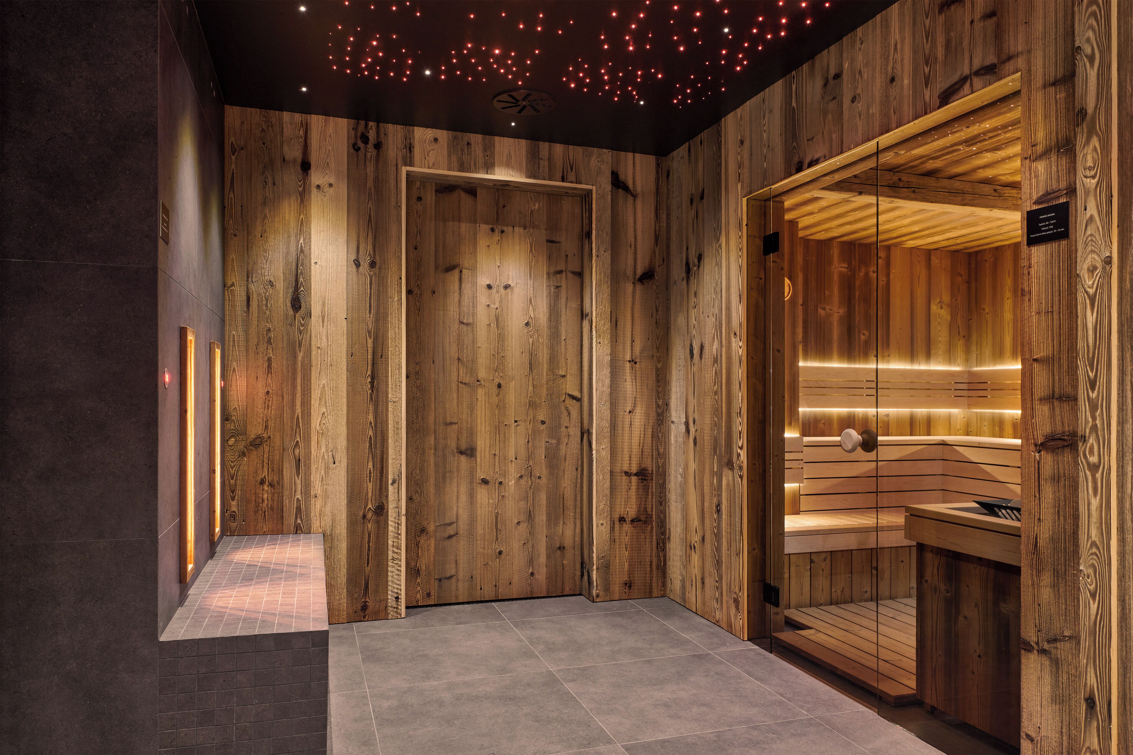 Interior de madera con zona de sauna, mostrador de recepción y suelo de baldosas.