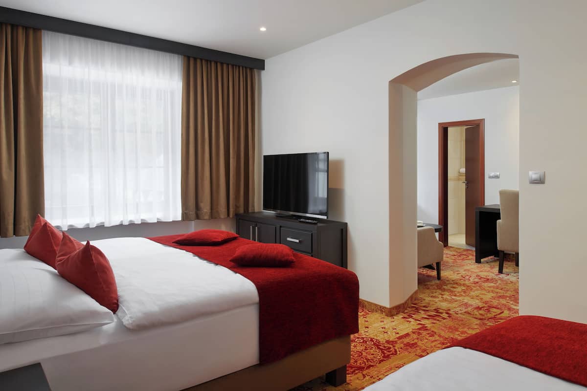 A hotel room with two beds, a television, and a desk.