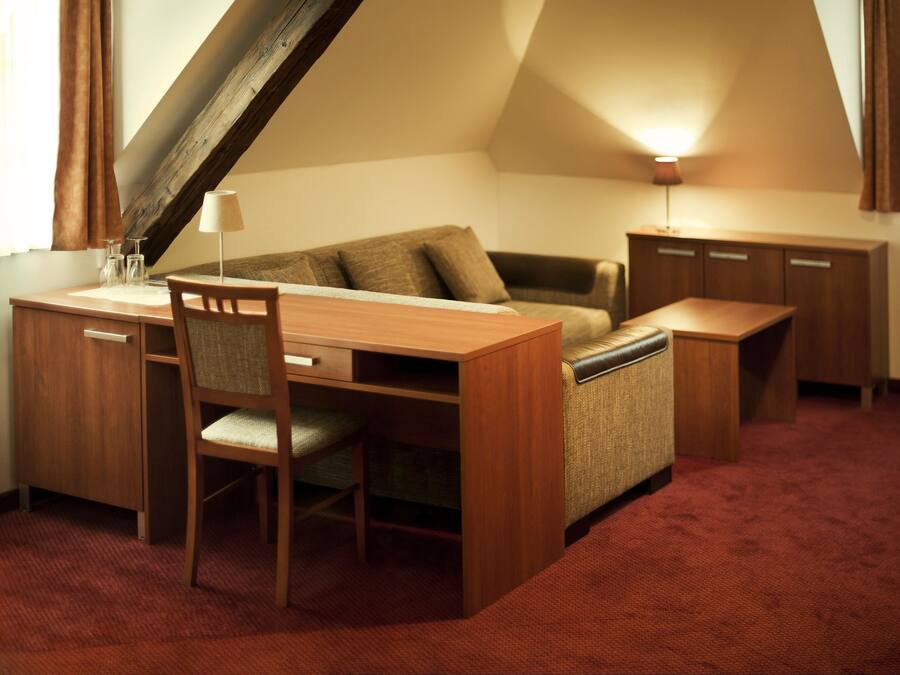 A compact room with a desk, a chair, a sofa, and a cabinet.