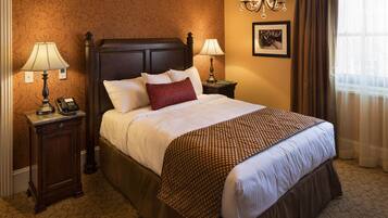 A hotel room with a large bed, two bedside tables with lamps, a framed picture on the wall, and a window with curtains.