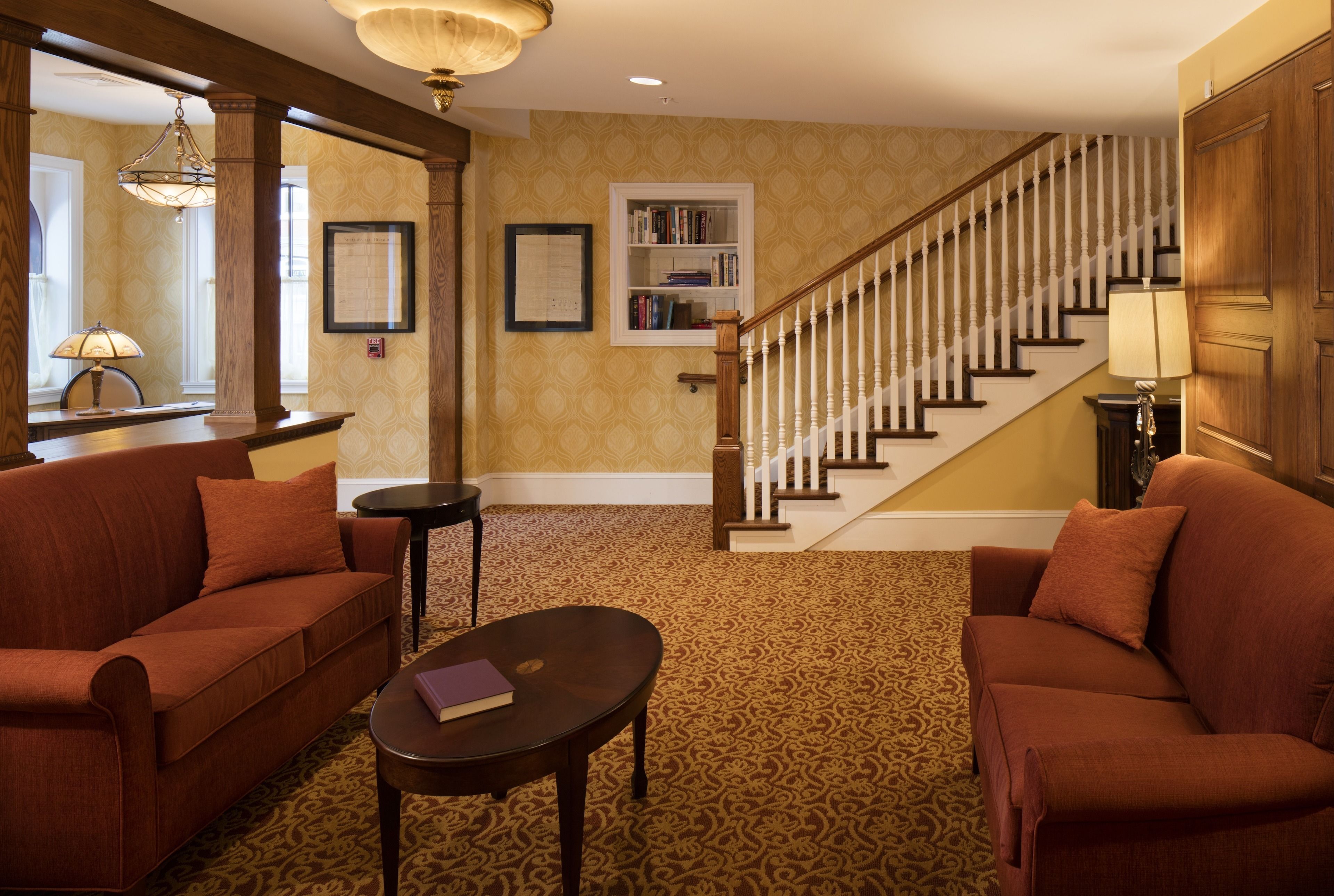 A spacious living room with a patterned carpet, two sofas, a coffee table, and a staircase leading to an upper floor.