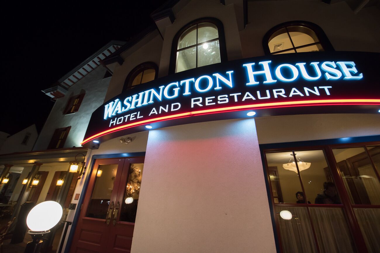Um hotel e restaurante chamado “Washington House”, com um letreiro iluminado em destaque.