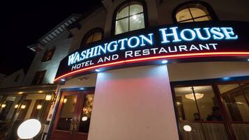 Um hotel e restaurante chamado “Washington House”, com um letreiro iluminado em destaque.