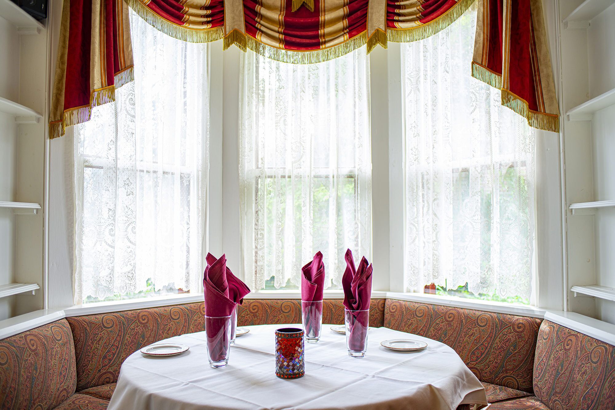 A dining area with a round table set for four, surrounded by patterned upholstery.