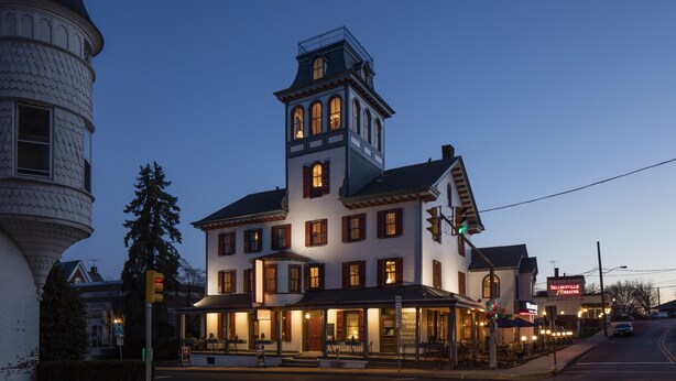 A historic building with a prominent tower, large windows, and a well-lit entrance. - Washington House Hotel (Sellersville)