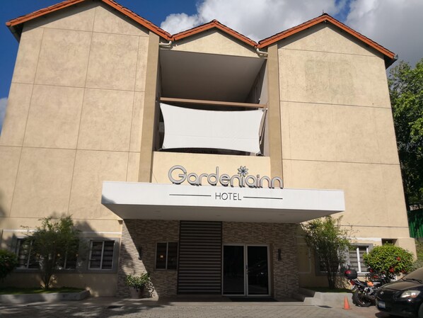 A hotel named 'Garden Inn' with a modern facade, large windows, and a gated entrance.