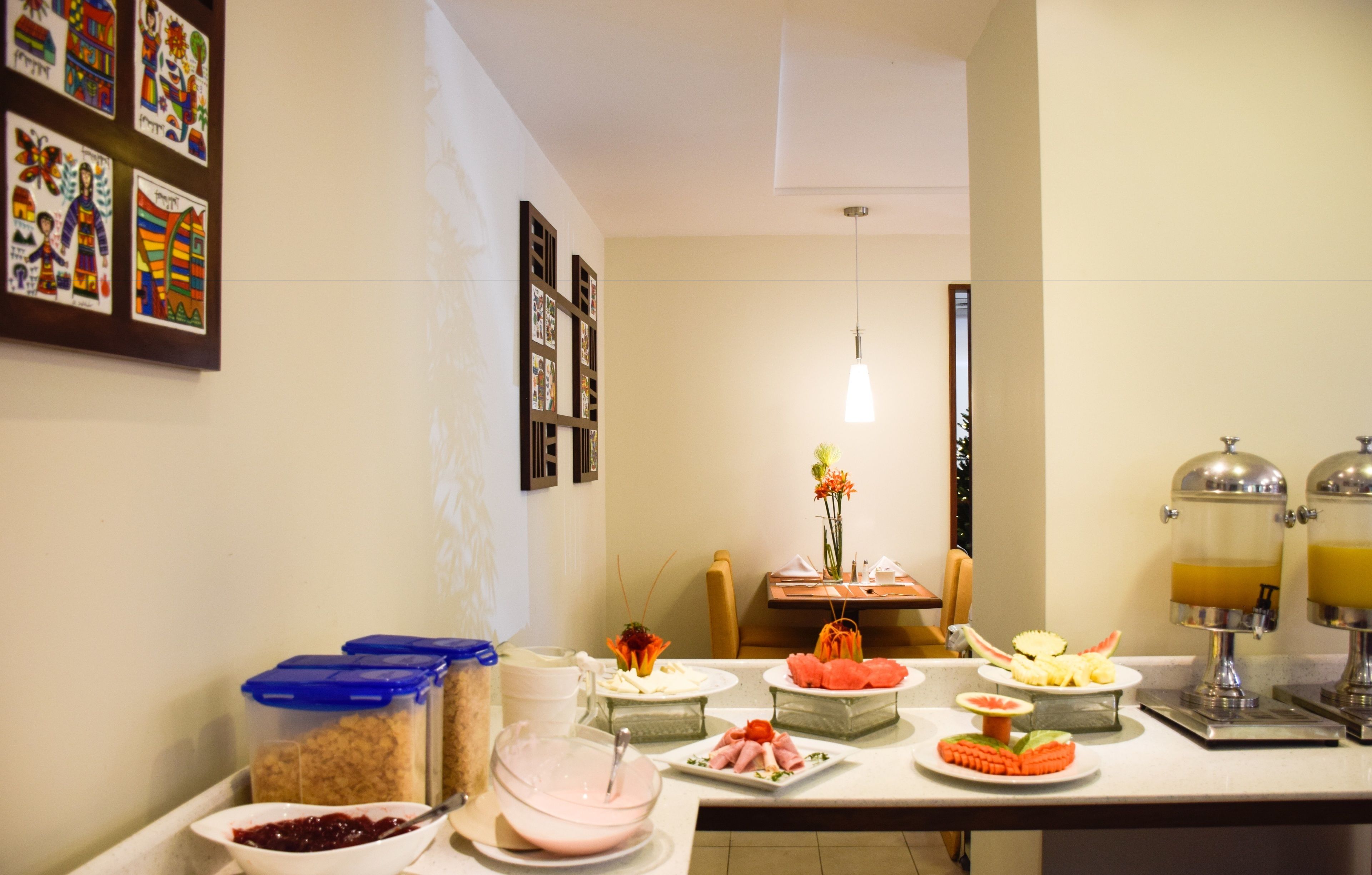 A buffet setup with various food items and a dining area with a chair and a vase of flowers.