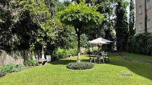 Ein gepflegter Garten mit einer Sitzgruppe in der Mitte, umgeben von üppiger Bepflanzung und verschiedenen Pflanzen.