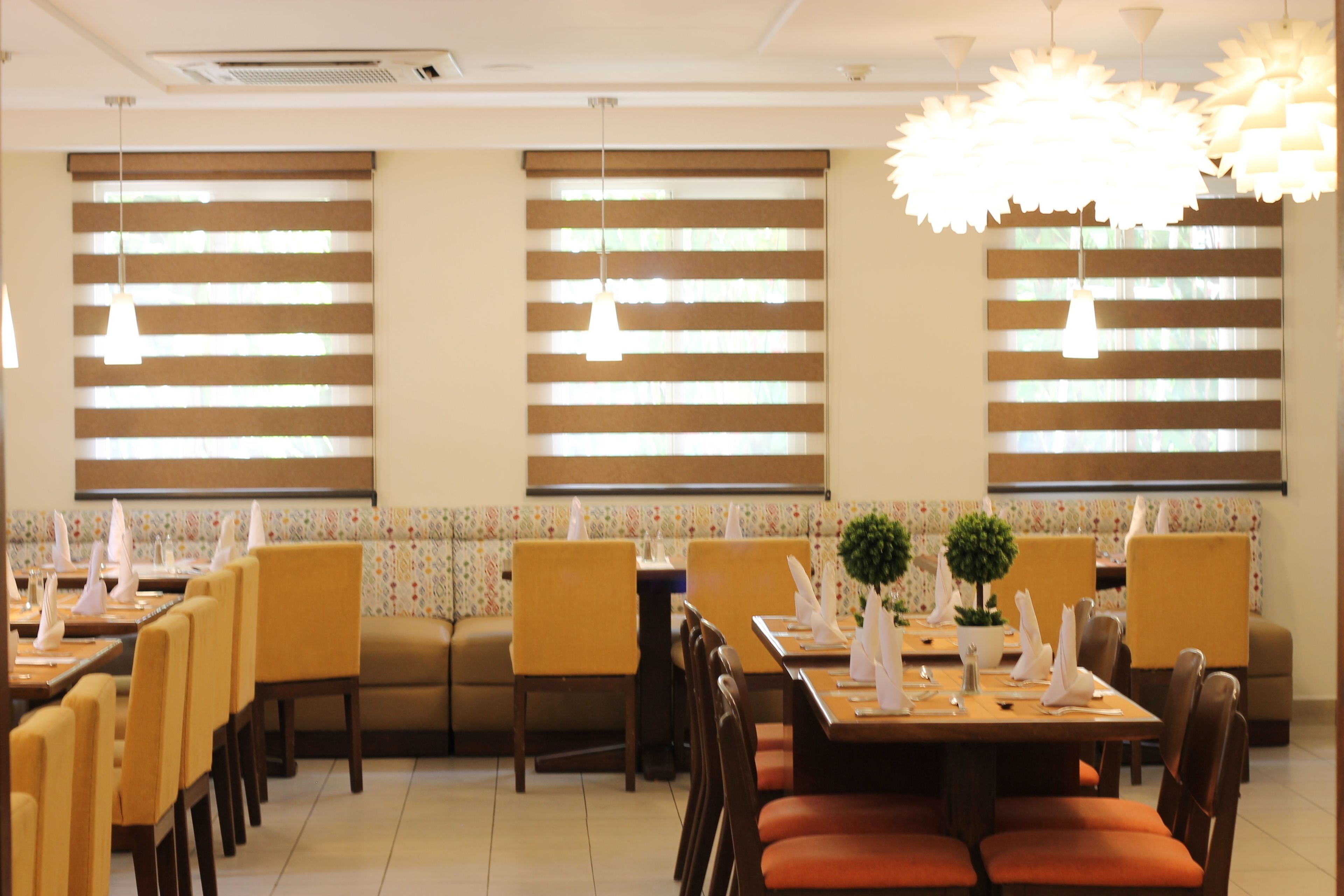 A restaurant with multiple dining tables and booths, each set with white napkins and silverware.