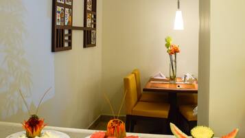 A dining area with a buffet table displaying various food items, a wall with framed pictures, and a dining table with chairs.