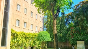 A building with a modern facade, a well-maintained lawn, and a swimming pool. - Hotel Gardenia Inn (San Salvador)