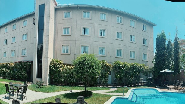 Ein mehrstöckiges Hotel mit Swimmingpool, Außenbereich und üppiger Bepflanzung.