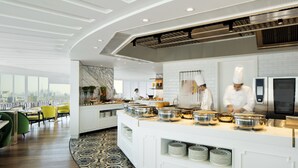 Une cuisine d’hôtel moderne avec un service de type buffet, une vue sur la ville et un sol à motifs.