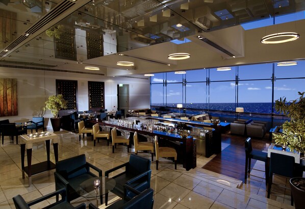 A modern bar area with seating and a view of the ocean.