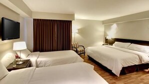 Een hotelkamer met twee bedden, een televisie, een lamp en een stoel.