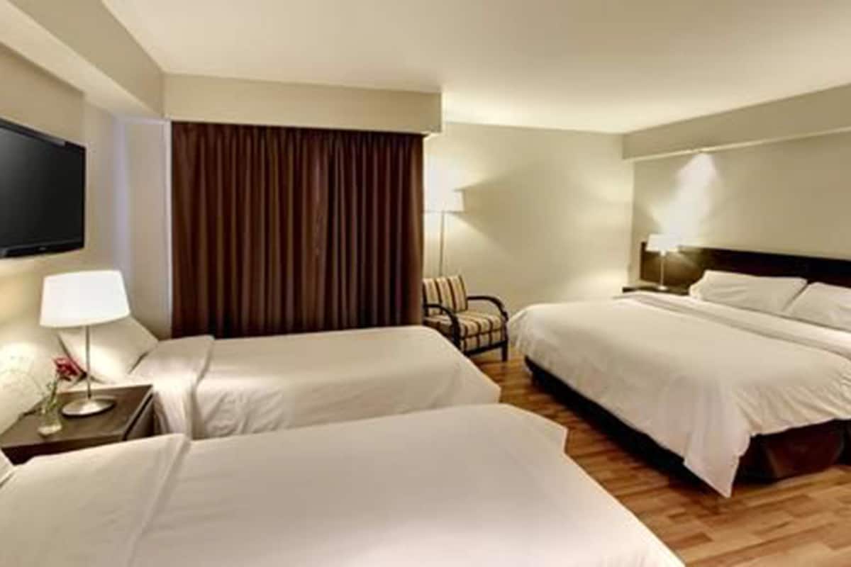 A hotel room with two beds, a TV, a lamp, and a chair.