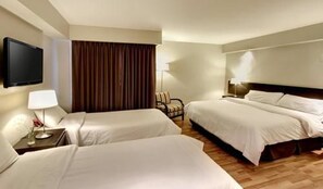 Una habitación de hotel con dos camas, televisión, lámpara y una silla.
