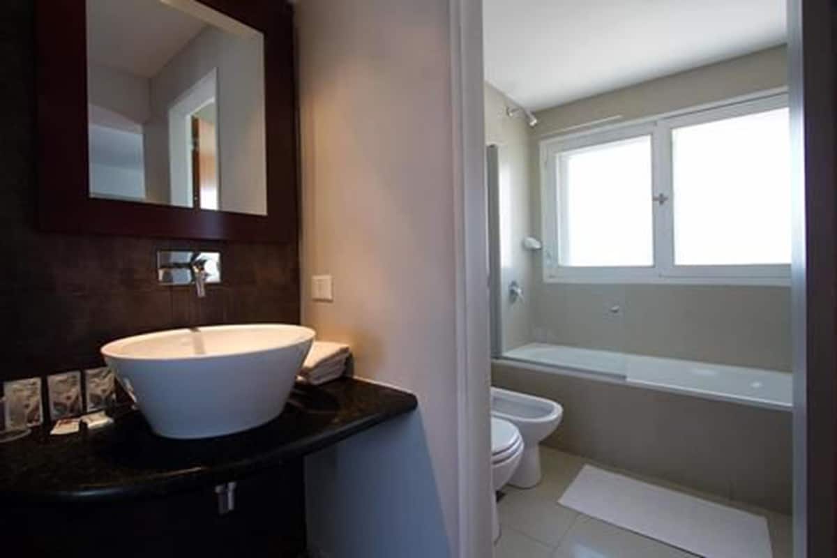 Un baño con un lavamanos grande de color blanco, un inodoro y una bañera.