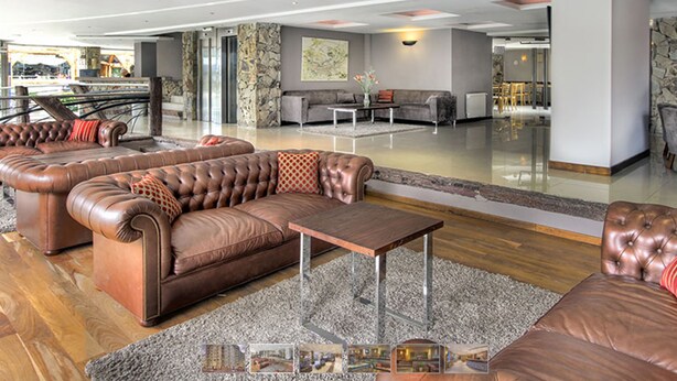 Een ruime woonkamer met leren banken, een salontafel en een accentmuur van steen.