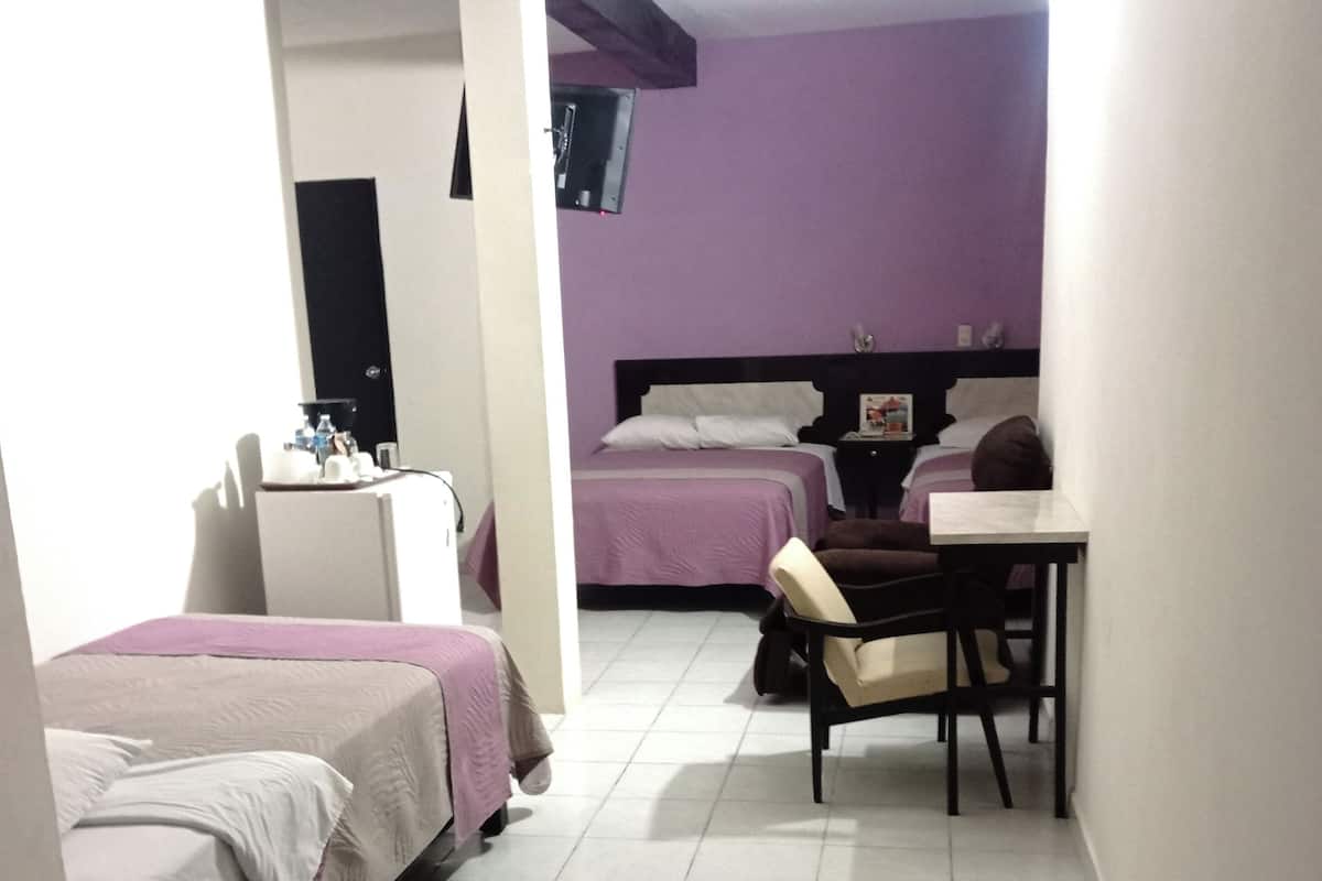 A hotel room with two beds, a desk, and a chair.