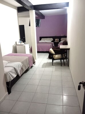 A hotel room with two beds, a desk, and a chair.