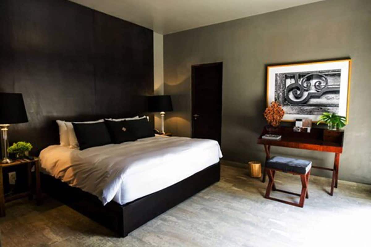A modern bedroom with a large bed, bedside tables, a desk, and a framed artwork on the wall.