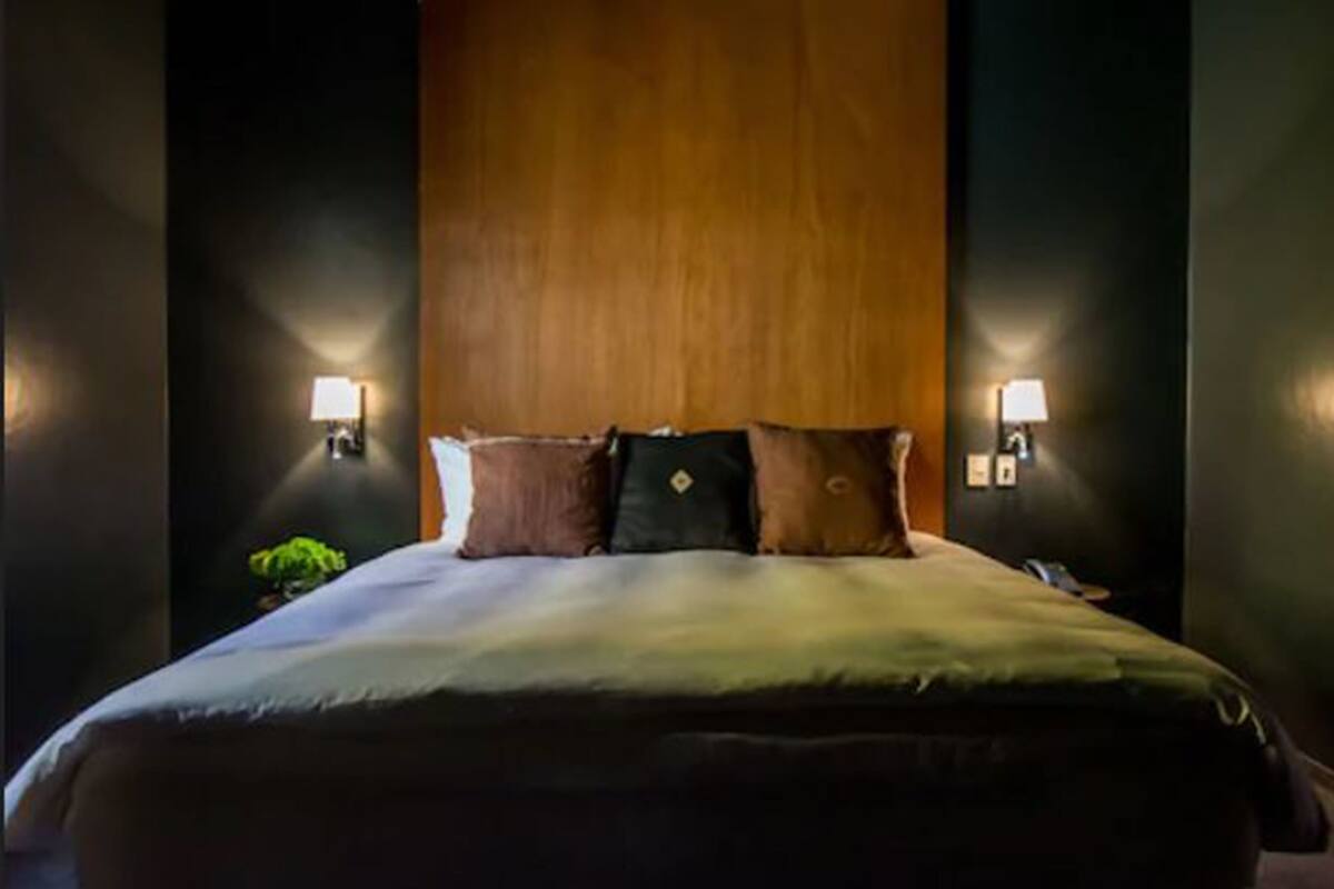A hotel room with a large bed, two bedside lamps, and a wooden headboard.