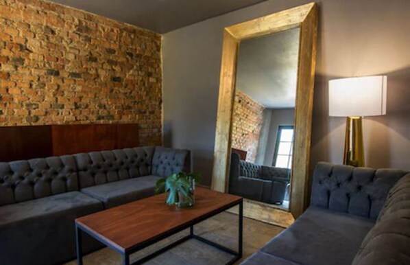 Una sala de estar moderna con pared de ladrillo, un espejo grande y un sofá.