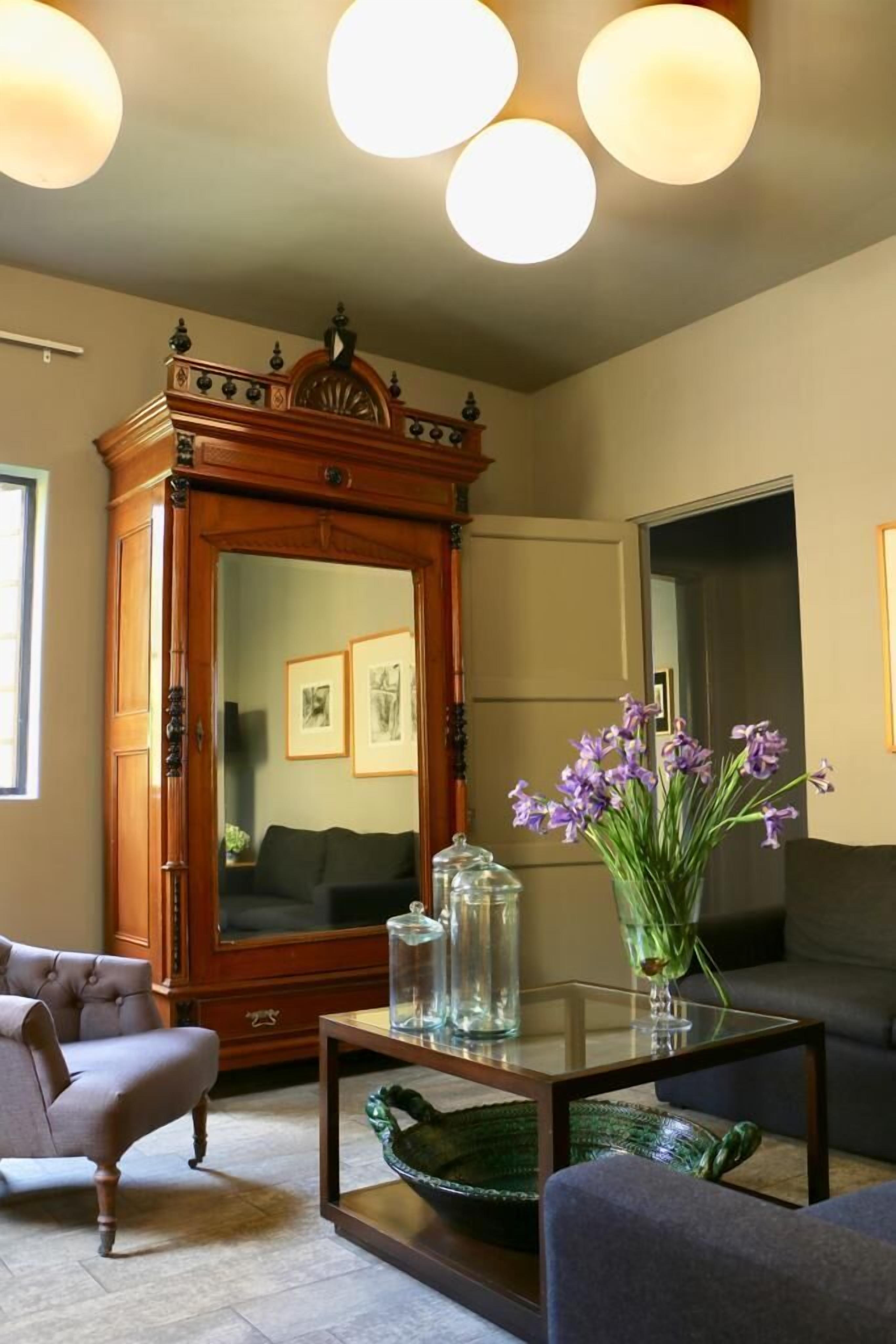 Una sala de estar con un mueble grande de madera, una mesa de centro de vidrio, un sofá y un jarrón con flores moradas.