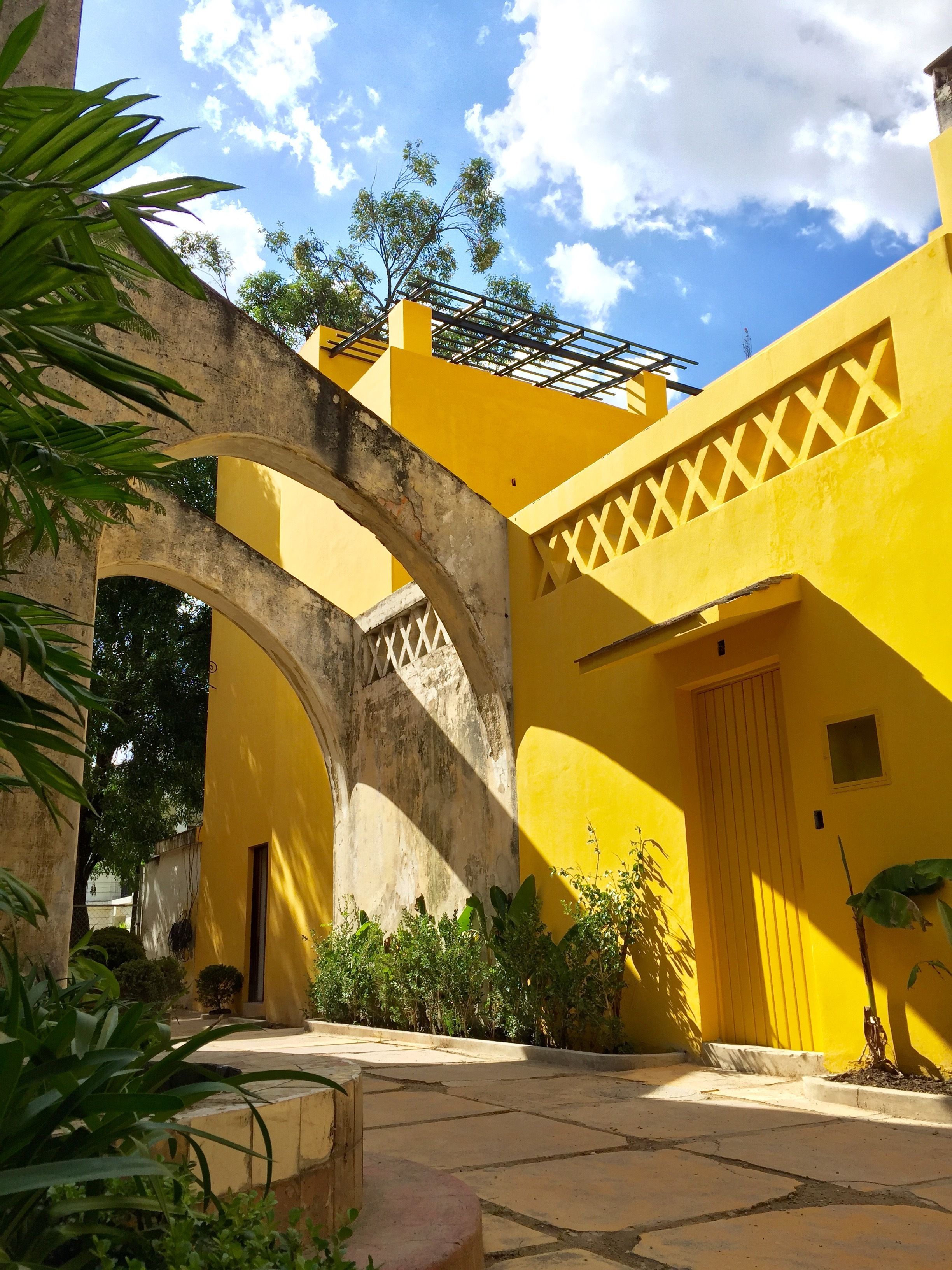 A courtyard with yellow walls, a wooden door, and a stone pathway.