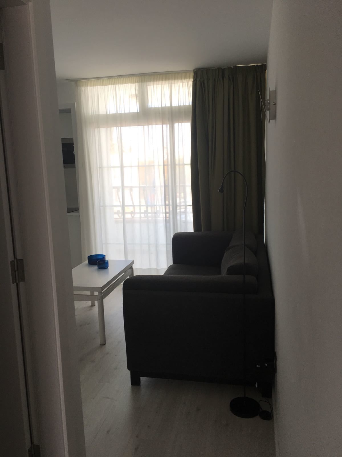 Ein Wohnzimmer mit einer Couch, einem kleinen Tisch und einem Fenster mit Vorhängen.